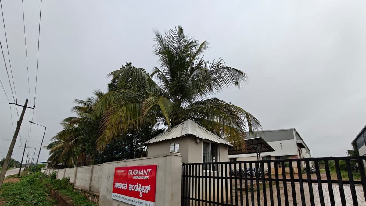 Red Sushant Industries signboard in English and Kannada on the factory boundary wall beside the main gate