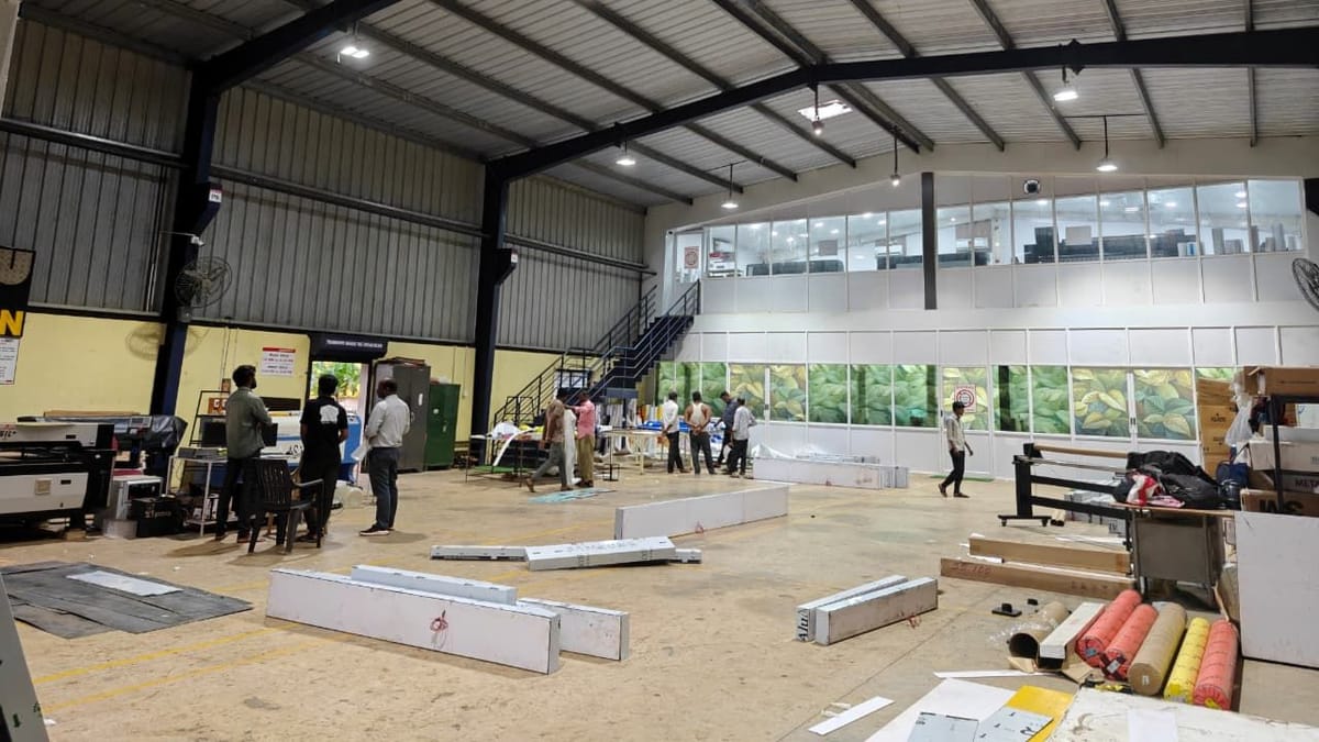 Production hall interior with staff working at the machines and long ACP sections laid out on the floor