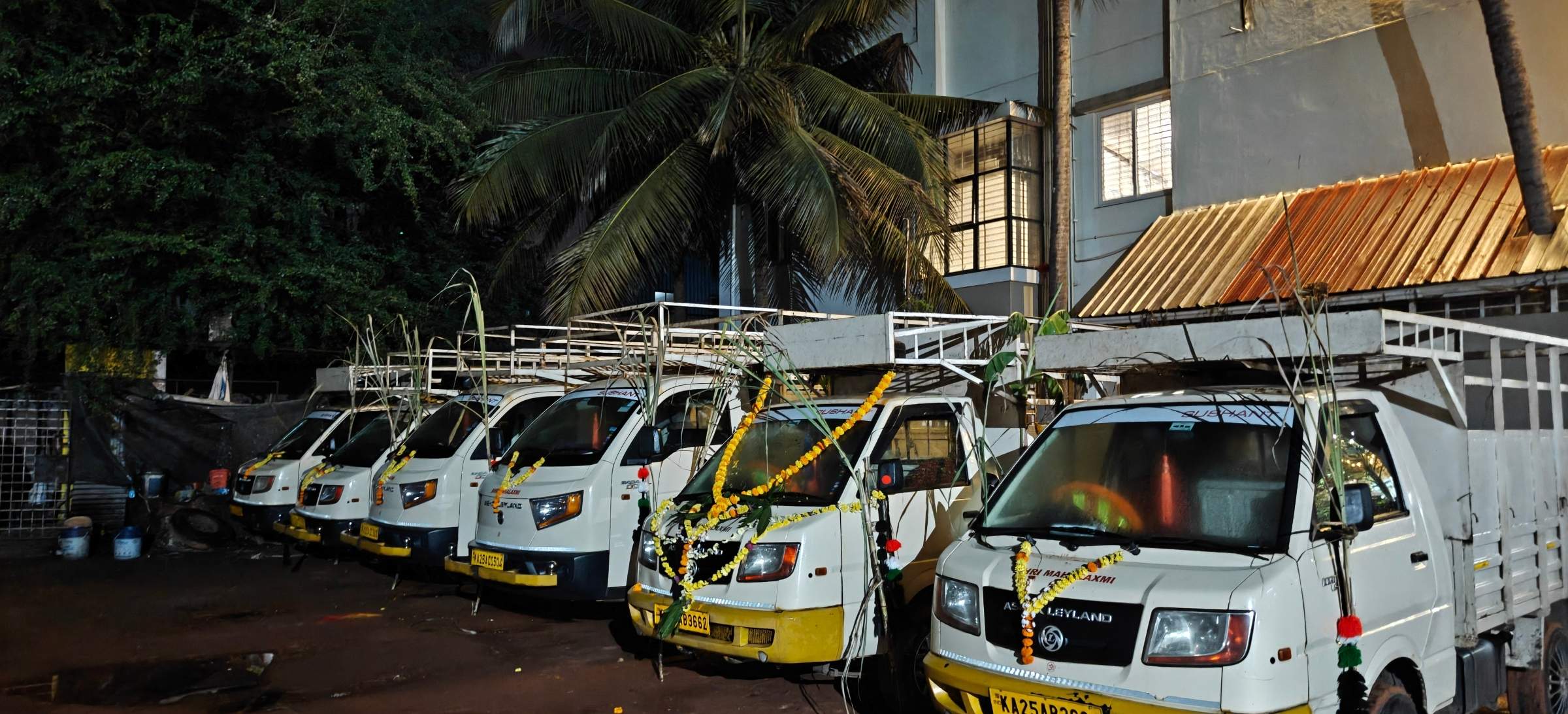 Row of white Sushant small cargo pickups in the yard