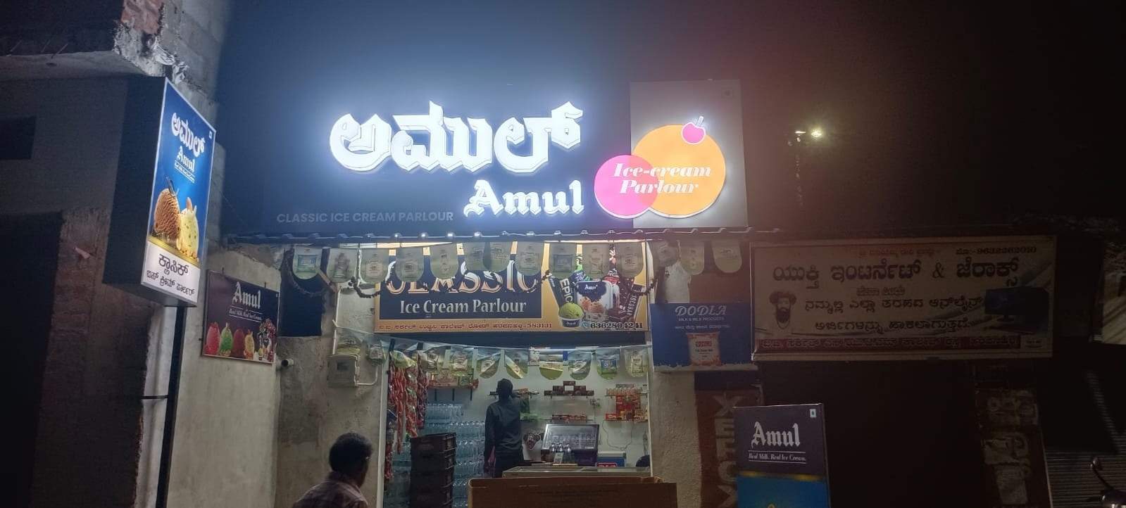 Illuminated Amul ice cream parlour shopfront at night